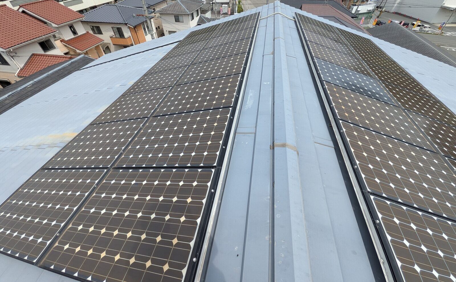 【施工前】屋根の両面に太陽光パネルが載った金属屋根。棟を挟んで南北にパネルが並ぶ