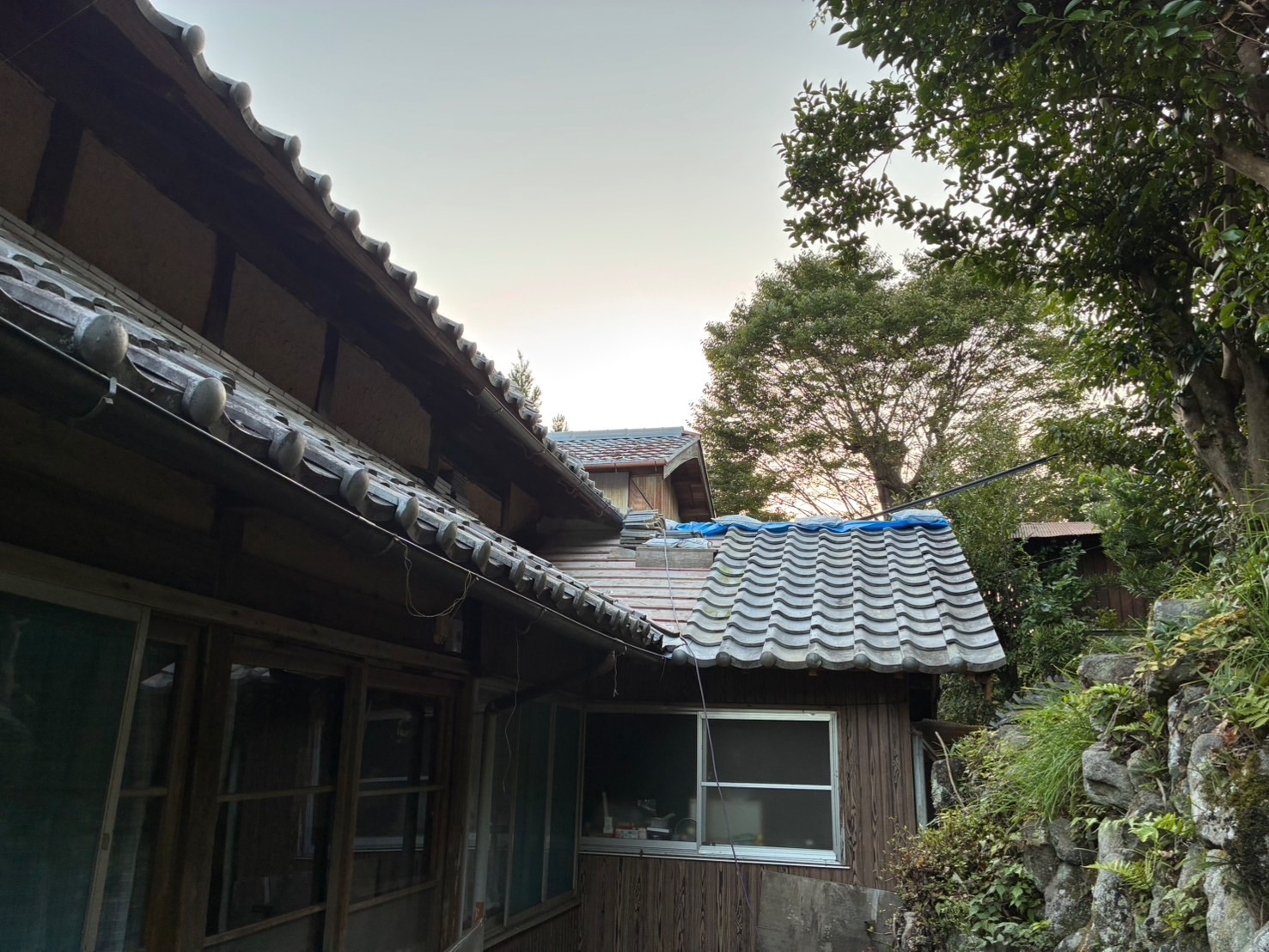 【施工中】瓦葺き直しが進む下屋。夕方まで作業を続け、未施工部はシートで養生